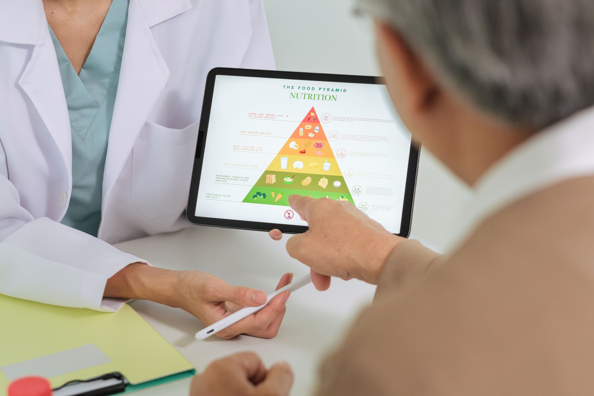 Doctor Explaining Healthy Eating and Food Pyramid to Senior Patient During Nutrition Counseling